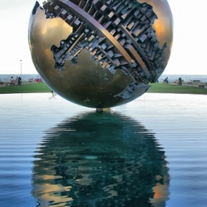 Eine kunstvoll verzierte Metallkugel schwebt scheinbar über dem Wasser.