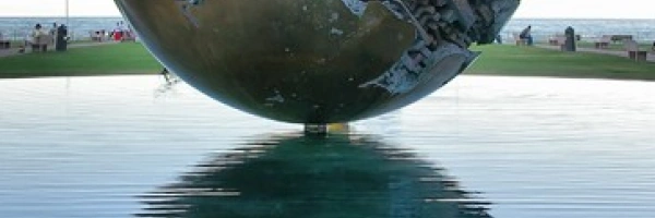 Eine kunstvoll verzierte Metallkugel schwebt scheinbar über dem Wasser.