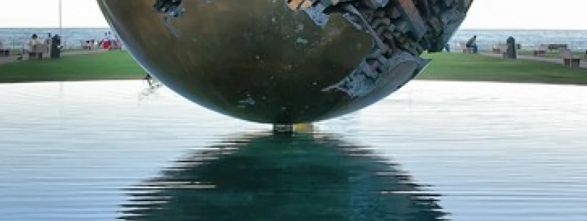 Eine kunstvoll verzierte Metallkugel schwebt scheinbar über dem Wasser.