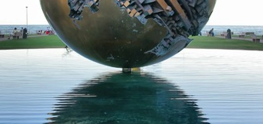 Eine kunstvoll verzierte Metallkugel schwebt scheinbar über dem Wasser.