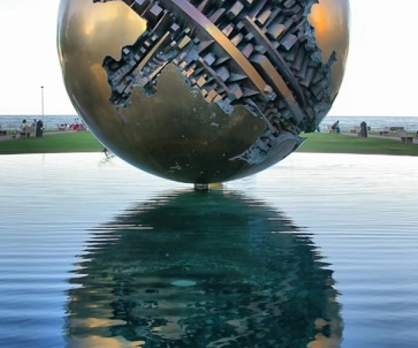 Eine kunstvoll verzierte Metallkugel schwebt scheinbar über dem Wasser.