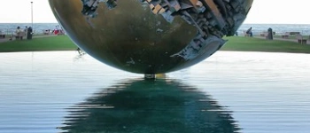 Eine kunstvoll verzierte Metallkugel schwebt scheinbar über dem Wasser.