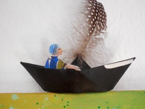 Eine gebastelte Figur sitzt in einem Papierboot.