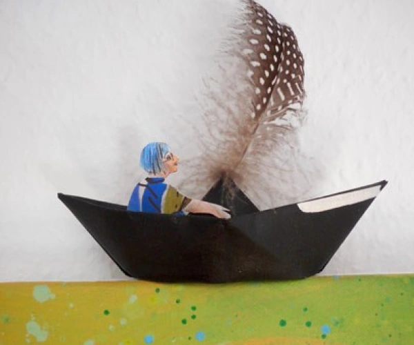 Eine gebastelte Figur sitzt in einem Papierboot.