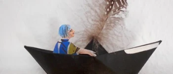 Eine gebastelte Figur sitzt in einem Papierboot.