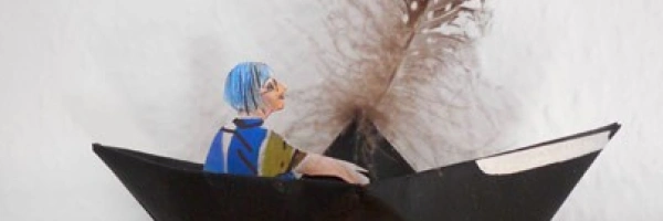 Eine gebastelte Figur sitzt in einem Papierboot.