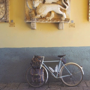 Ein Fahrrad lehnt an einer Wand, die mit Skulpturen, von Wappen und einem Löwen, geschmückt ist