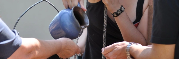 Ein Wasserkrug wird über offenen Händen ausgegossen.