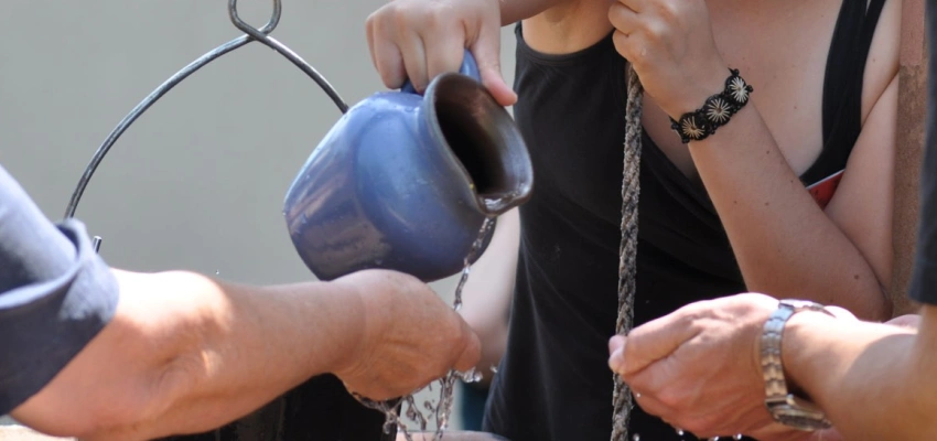 Ein Wasserkrug wird über offenen Händen ausgegossen.