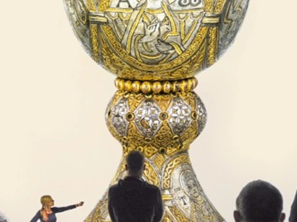 Menschen sind um einen großen goldenen Kelch versammelt.
