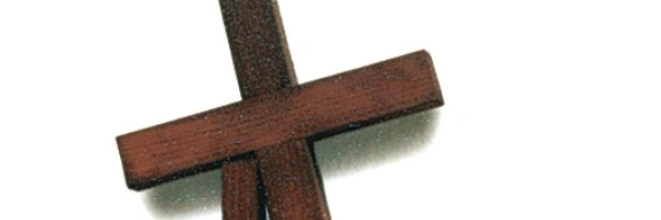 Ein Kreuz stützt sich auf einen Holzpfeiler