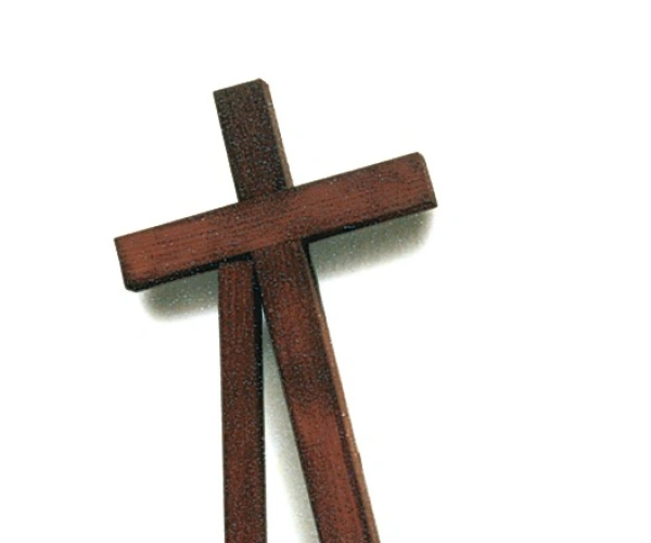 Ein Kreuz stützt sich auf einen Holzpfeiler