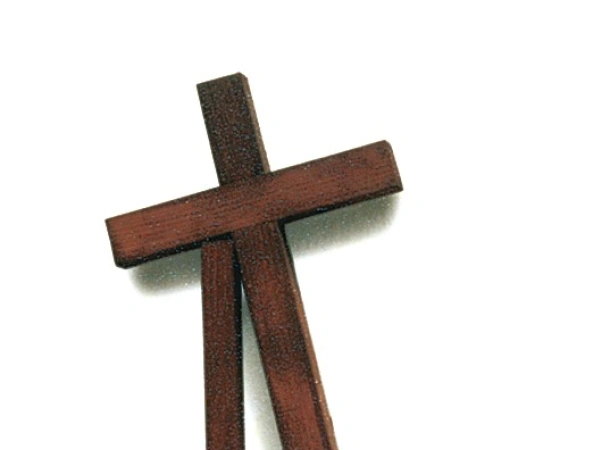Ein Kreuz stützt sich auf einen Holzpfeiler