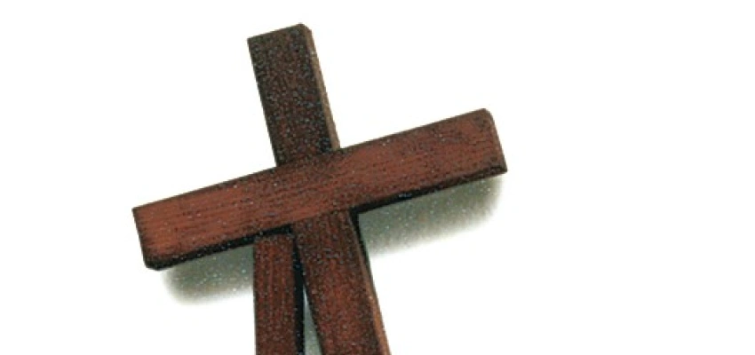 Ein Kreuz stützt sich auf einen Holzpfeiler