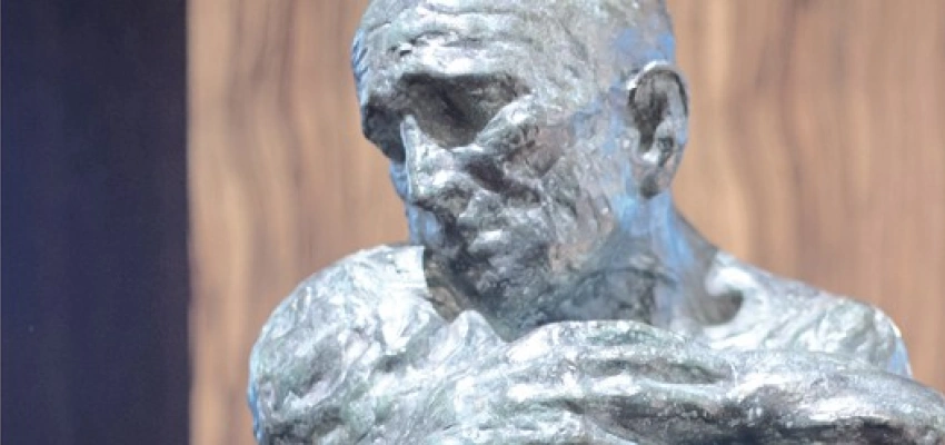 Eine Skulptur zeigt einen Menschen, der einen anderen umarmt, der alle Kräfte verloren zu haben scheint.