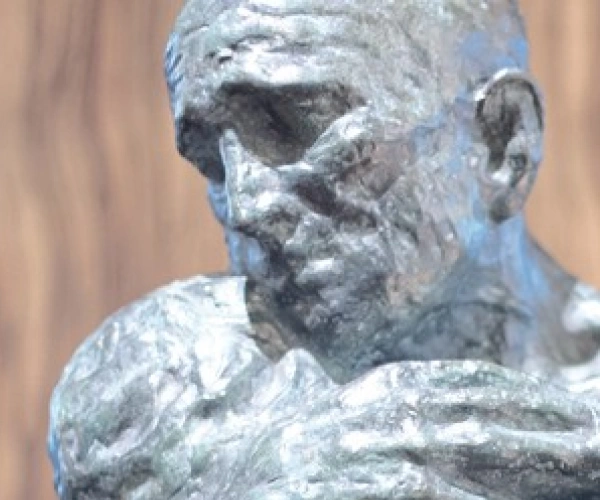 Eine Skulptur zeigt einen Menschen, der einen anderen umarmt, der alle Kräfte verloren zu haben scheint.