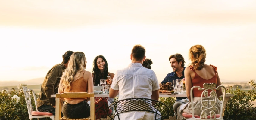 Eine Gruppe junger Menschen sitzt lachend an einem Tisch.