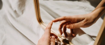 Eine Hand berührt ihr Spiegelbild, in einem Spiegel.