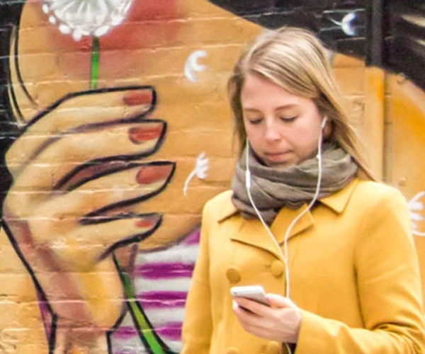 bemalte Wand, davor ein Mädchen am Handy