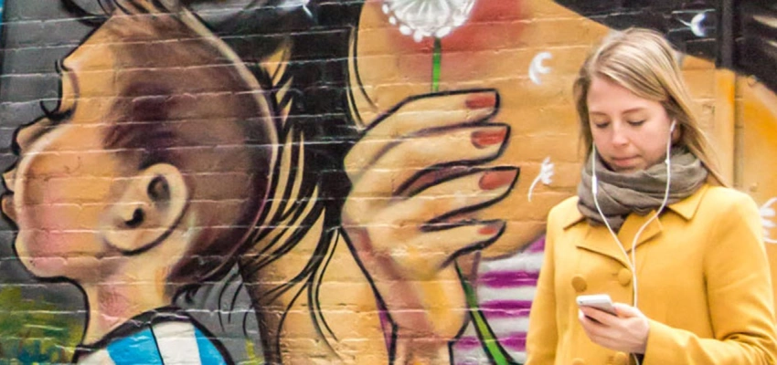 bemalte Wand, davor ein Mädchen am Handy
