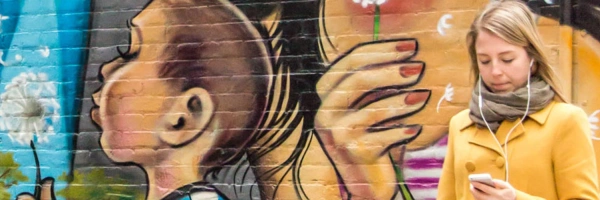 bemalte Wand, davor ein Mädchen am Handy