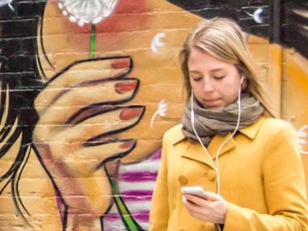 bemalte Wand, davor ein Mädchen am Handy