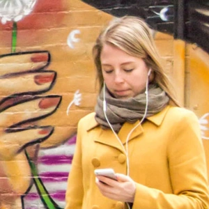 bemalte Wand, davor ein Mädchen am Handy