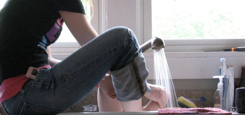 Eine Frau wäscht ihre Füße im Spülbecken.