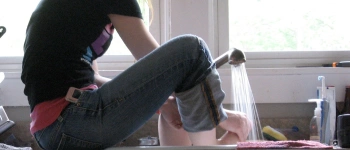 Eine Frau wäscht ihre Füße im Spülbecken.