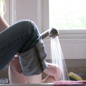 Eine Frau wäscht ihre Füße im Spülbecken.