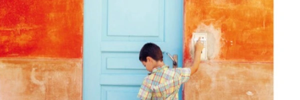 Ein Kind mit Koffer in der Hand klingelt an einer Haustür