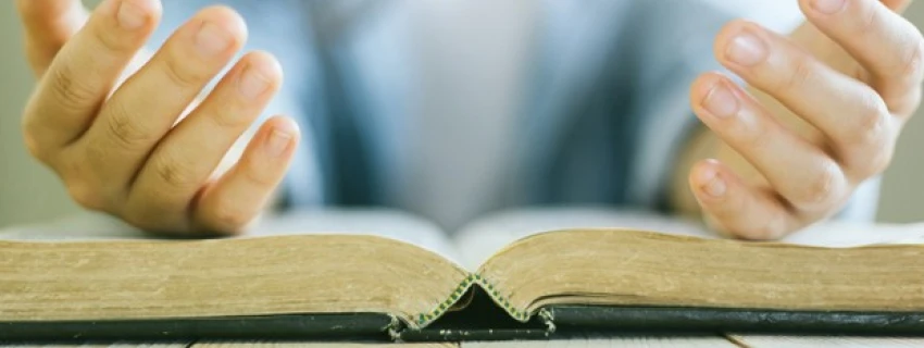 Offene Hände liegen auf einer aufgeschlagenen Bibel
