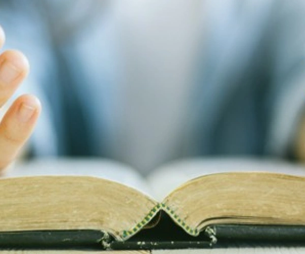 Offene Hände liegen auf einer aufgeschlagenen Bibel