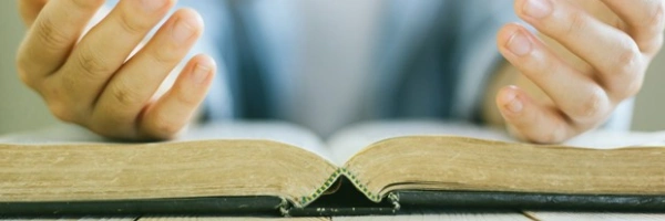 Offene Hände liegen auf einer aufgeschlagenen Bibel