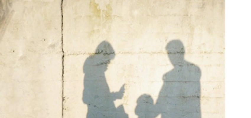 Eine Familie wird als Schatten auf eine Betonwand geworfen.
