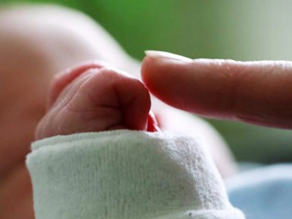 ein Zeigefinger berührt die Hand eines Babys