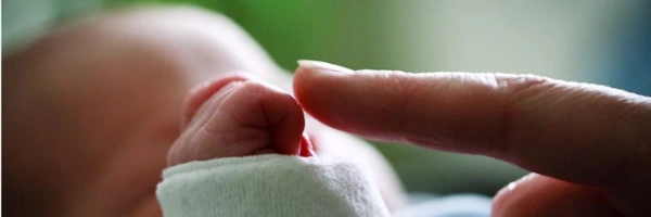 ein Zeigefinger berührt die Hand eines Babys