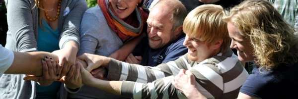 viele lachende Menschen ziehen zusammen an einem Arm