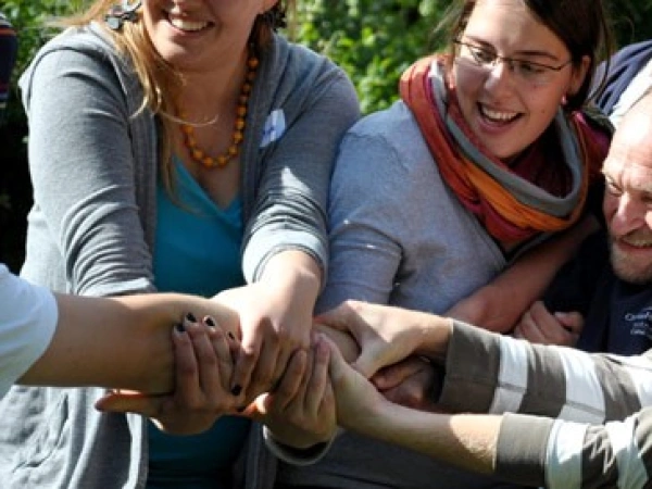 viele lachende Menschen ziehen zusammen an einem Arm