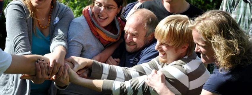 viele lachende Menschen ziehen zusammen an einem Arm