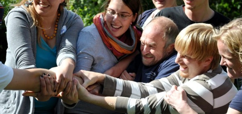 viele lachende Menschen ziehen zusammen an einem Arm