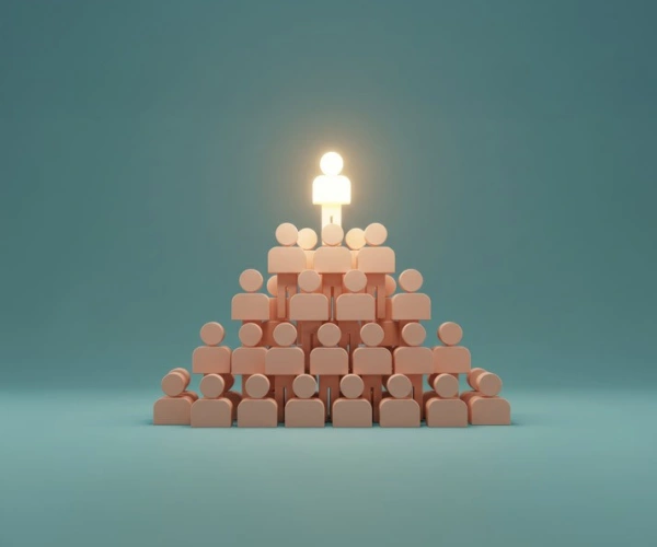 Eine Menschenpyramide. Der Mensch an der Spitze leuchtet.