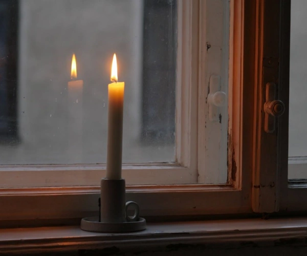 Brennende Kerze auf einem Fensterbrett