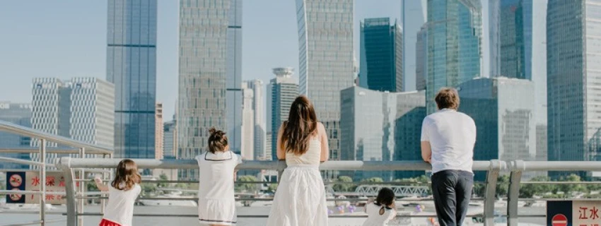Familie steht an einem Geländer vor einer Skyline