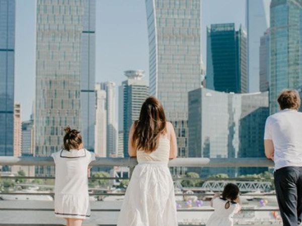 Familie steht an einem Geländer vor einer Skyline