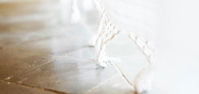 Weiße Gardine streift über den Fließenboden