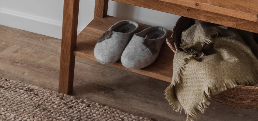 Kleines Regal mit einem Paar Filzhausschuhen und einem Korb mit Schals