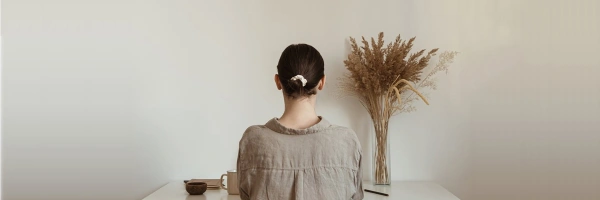 Frau vor leeren Wand an einem Schreibtisch sitzend