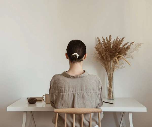Frau vor leeren Wand an einem Schreibtisch sitzend