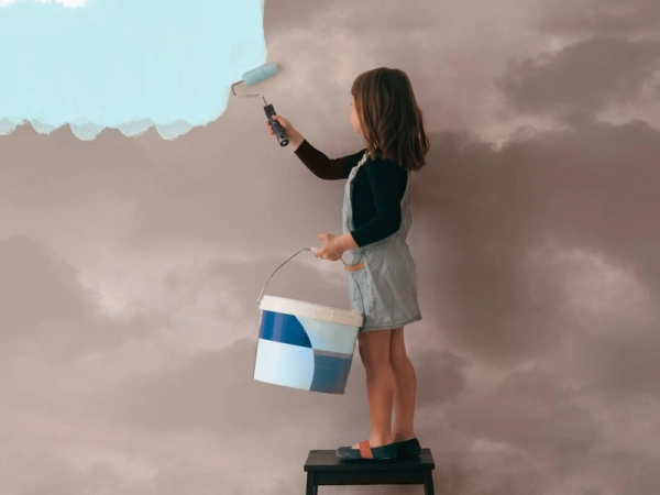 Kind streicht eine graue Wolkenwand mit himmelblauer Farbe